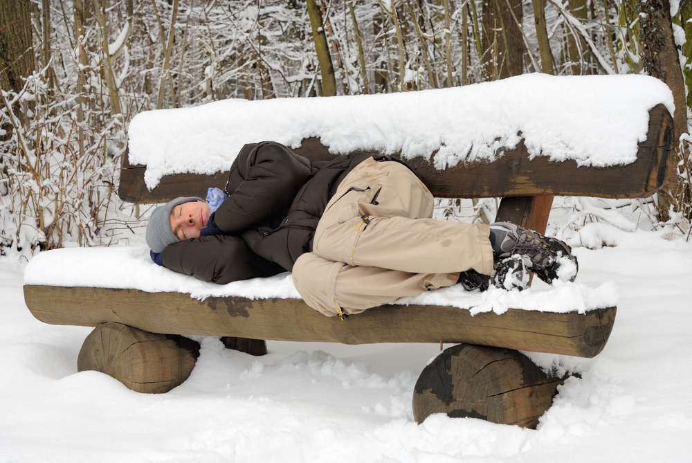 Спит на лавочке зимой в снегу